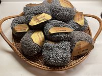 13 balls of soft grey nubby textured yarn in a wicker basket, threads of black throughout.