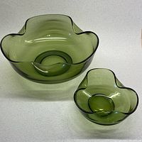 Two green glass bowls with scalloped edges showing size difference and shape