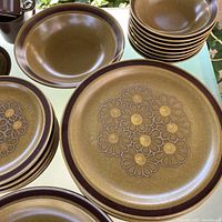 Close-up showing dinner plate with floral pattern and chocolate rim in speckled mustard color.