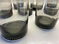 Close-up photo showing the textured woven pattern at the bottom of the smokey grey lowball glass and the smooth cylindrical walls above.