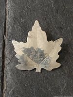 Photo showing the full front side of the hand hammered maple leaf pin in sterling silver, clear detailing of leaf veins and edges.