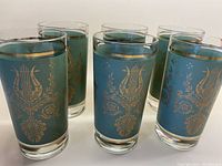 Group of all six green frosted mid-century tumblers with gold emblem designs.