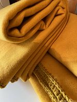 Folded blankets stacked showing color, texture, and hand-stitched edging.