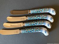Four PRILL knives neatly lined up showing stainless steel blades and colorful ceramic handles with peacock feather design.