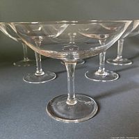 Close-up view of the front crystal champagne glass showing wide shallow bowl, stem, and footed base.