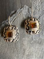 Pair of vintage sterling silver and amber drop earrings shown on a slate background, showing oxidized edges and amber stones