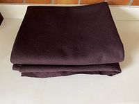Folded piece of rich burgundy wool blend fabric showing smooth surface and thickness.