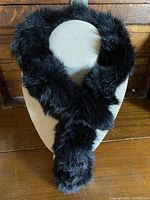 Front view of black dyed rabbit fur scarf displayed on neutral fabric mannequin bust showing its soft plush texture and length.