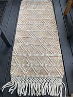 Full view of the wool runner rug showing cream and pale tea colors with geometric raised patterns and fringe ends.