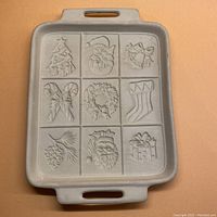 Full view of the rectangular ceramic cookie pan with handles and 9 embossed Christmas motifs for shortbread cookies.