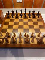 Chessboard with wooden chess pieces set up on it, showing full view of pieces and board