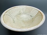 Large ceramic bowl showing interior surface with cream base, brown speckles and blue swirl pattern.