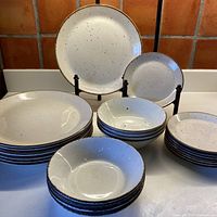 Overview of stacks: 8 dinner plates, 8 dessert plates, 8 cereal bowls with one dinner and one dessert plate on display stands.