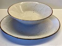 Oval platter and large serving bowl stacked together showing the cream base with chocolate speckles and chocolate rim