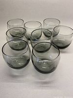 Eight smokey grey round Roly Poly scotch glasses arranged in two rows, showing their shape and color.