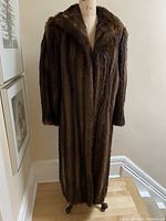 Full front view of the long mink fur coat on a dress form, showing overall condition and length.