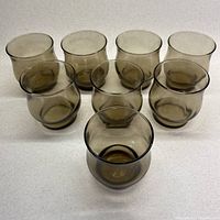 Front view showing 8 smokey grey tulip-shaped old fashioned/lowball glasses arranged in two rows.