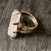 Top and angled view of sterling silver ring with long rectangular rose quartz stone held by thick prongs.