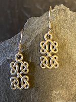 Pair of sterling silver Celtic knot design drop earrings against dark slate background