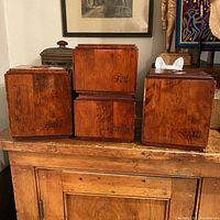 Four wooden canisters labeled Flour, Coffee, Tea, and Sugar, stacked in two rows on a wooden cabinet.