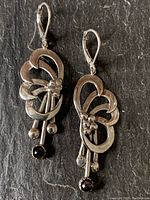 Full view of the pair of vintage sterling silver earrings with amethyst stones on a dark background.