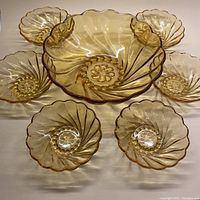 Full set of 7 amber glass bowls: 1 large bowl surrounded by 6 smaller bowls showing overall design and scalloped edges.