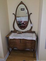 Photo of the oak antique dresser with oval mirror, showing front view with decorative side supports and carved top of mirror frame