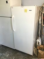 Front view of white upright freezer next to another appliance.