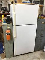 Front view of closed Maytag refrigerator showing top freezer door, bottom fridge door, and handle badge.