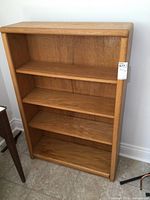 Front view of the solid oak bookshelf showing three shelves and natural wood finish.