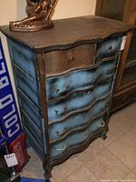 Front perspective of oak dresser showing curved drawers painted in distressed blue with missing handles and some extra handles inside a drawer.