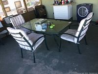 Full view of the patio set showing glass top table and cushioned chairs