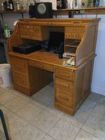 Full front view of the oak roll top desk with open workspace and visible drawers.