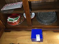 Glass serving platters, ceramic sectional dish, and various plastic dishes with a boxed item below them.