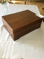 Closed top view of polished wooden chest on white tablecloth.