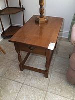 View of solid wood Vilas end table showing front and side with drawer and turned legs