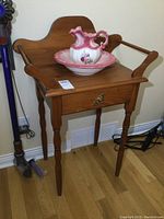 Solid pine washstand with ceramic bowl and pitcher on top, showing overall piece and condition.