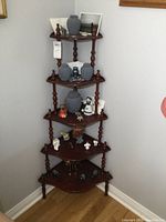 Full view of the 5-tier what not corner shelf filled with various small decorative items to show size and usage.