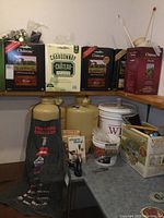Photo showing Chateau boxed wine making kits, plastic jugs, apron, recipe books, and accessories on countertop and shelf.
