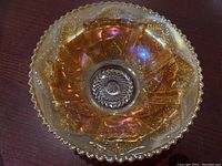 Overhead view showing the marigold iridescent finish and scalloped beaded rim of the carnival glass bowl.