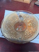 Top view of carnival glass bowl showing grape clusters and leaves pattern with central tree branch handle.