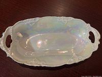 Top-down view of the iridescent antique German porcelain dish showing its shape, handles, and glossy finish.