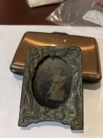 Antique metal picture frame with ornate nature-inspired design and sepia toned photo of two children inside.