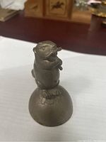 Front side view showing beaver holding stick, standing on rounded base.