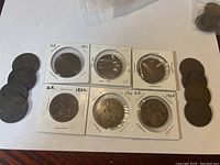 Coins arranged with six coins in paper holders showing dates 1861, 1862, 1891, 1896, 1908, 1909, and several other coins loose to sides.