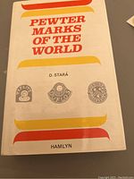 Front cover of the hardcover book titled Pewter Marks of the World, author D. Stará, publisher Hamlyn, showing sample pewter marks on cover.