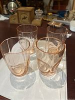 Four pink Depression glass bullseye pattern tumblers shown together on a white surface, highlighting their size and shape.