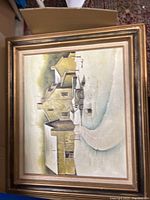 Framed painting showing a snow-covered country winter scene with buildings and sky.