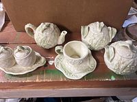 Full view of the stoneware set showing two teapots, double handled bowls, cup and saucer, and small lidded bowls on platter.