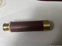 Telescope fully collapsed showing brass and leather wrapped barrel with decorative lacing.